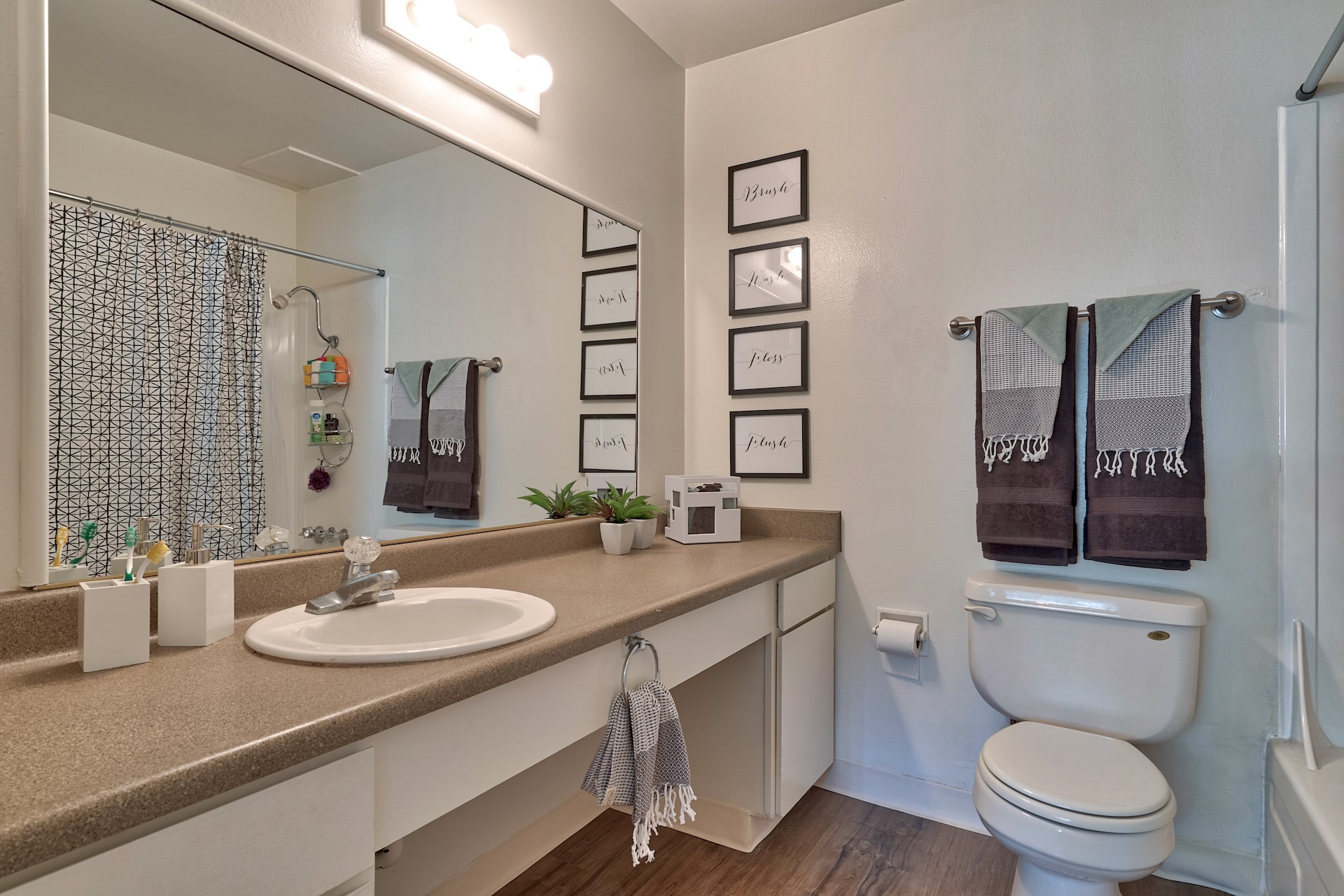 bathroom with single sink, large mirror, and toilet beside a garden tub at the spoke apartments