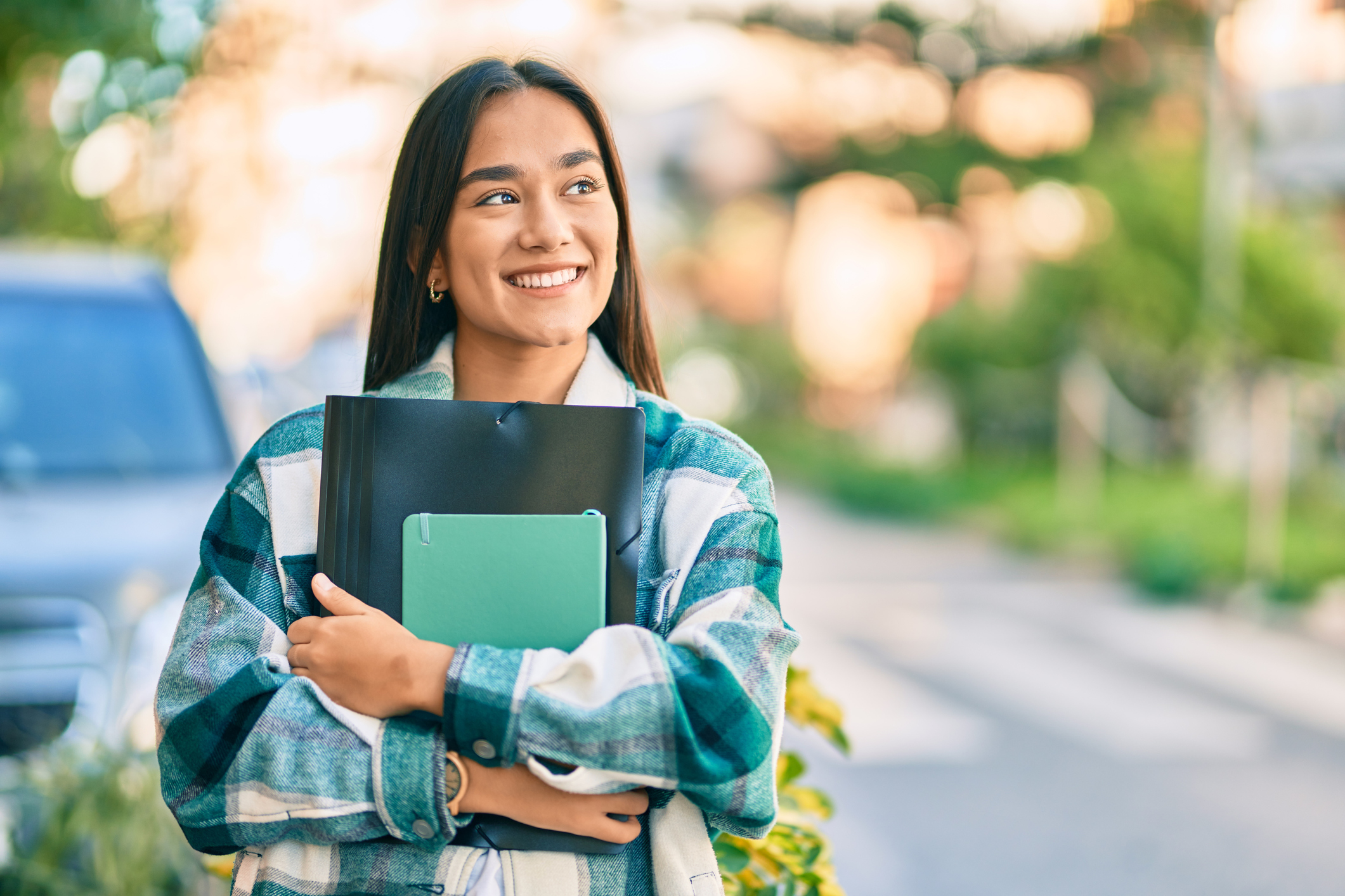 Young student smiling happy holding folder at the city.